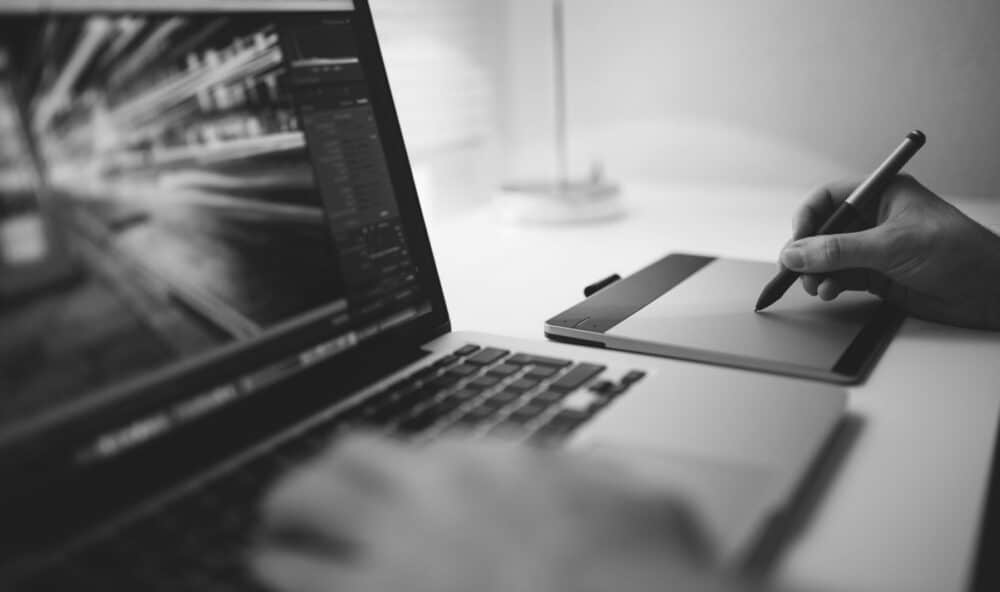 Person working on digital design with a graphics tablet and laptop.
